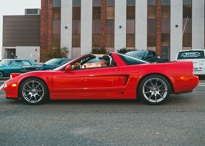 A red sports car driven by a man, a common sight for a cringe midlife crisis.
