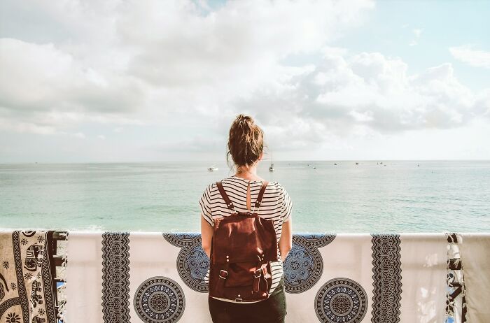 A woman with a backpack gazes at the sea, contemplating the truths about being married.