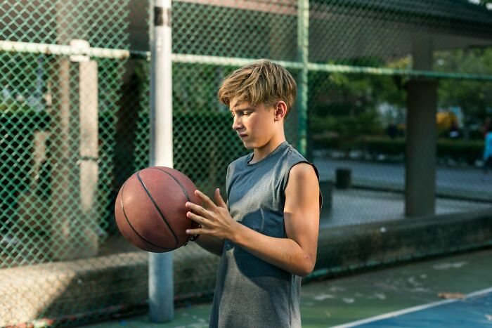A young boy holding a basketball on a court. Interesting neighbors.