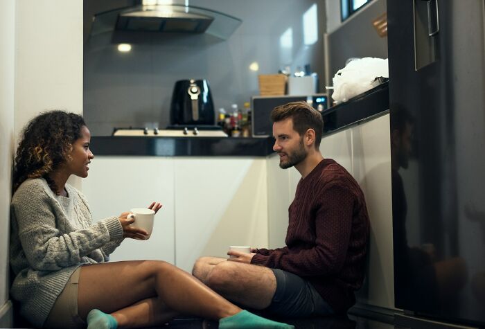 A couple sitting on the kitchen floor, drinking coffee and talking, showing truths about being married.