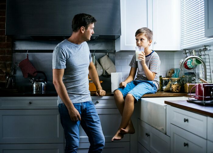 A father and son in the kitchen, with the boy drinking milk, possibly reflecting actions of a horrible parent.