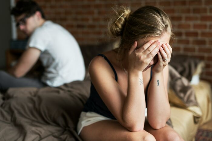 A woman crying, covering her face, with a man turning his back in the background. Illustrates interesting neighbors.