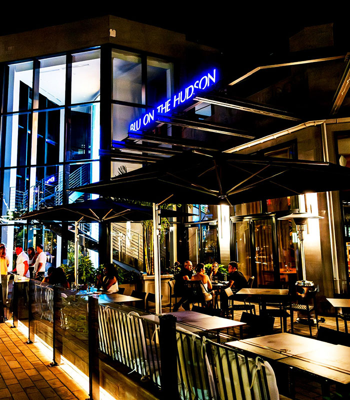 An exterior night shot of a restaurant, Blu on the Hudson, with neon signs and outdoor seating, where the disabled customer was served the offensive birthday message.