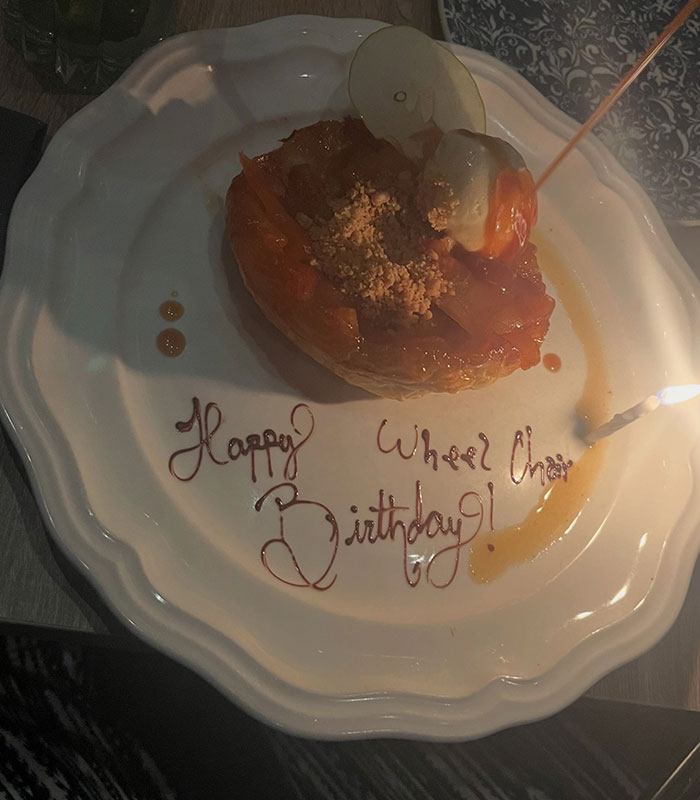 Dessert with a candle on a white plate, featuring an offensive birthday message for a disabled customer. Restaurant breaks silence after offensive birthday message.