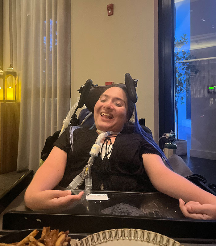 A disabled customer in a wheelchair, smiling at a restaurant, before receiving the offensive birthday message dessert.