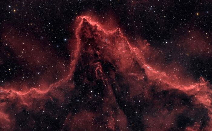 A majestic red nebula resembling a mountain range against a starry black sky, an amazing astrophotography award winner.