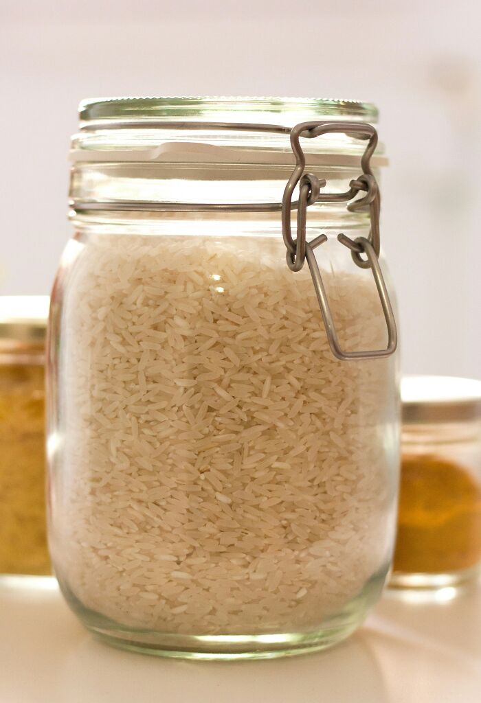 A clear glass jar filled with white rice, a common staple food that newcomers might find surprising in America.