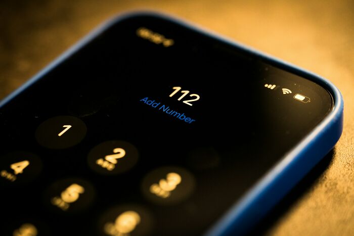 A close-up of a smartphone screen showing the number 112 being dialed, representing an emergency call in the medical field.