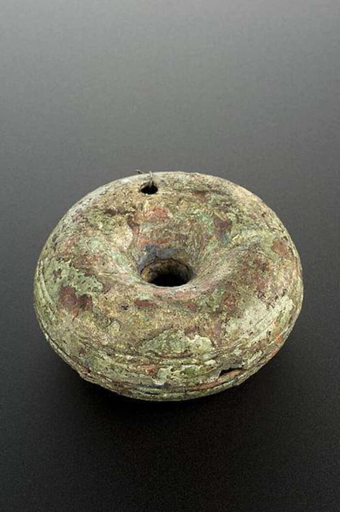 A circular, weathered artifact with a hole in the center, hinting at terrifying methods and tools doctors used in the past.
