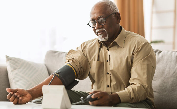 An elderly male patient self-monitoring blood pressure at home, demonstrating proactive health management patients undertake.