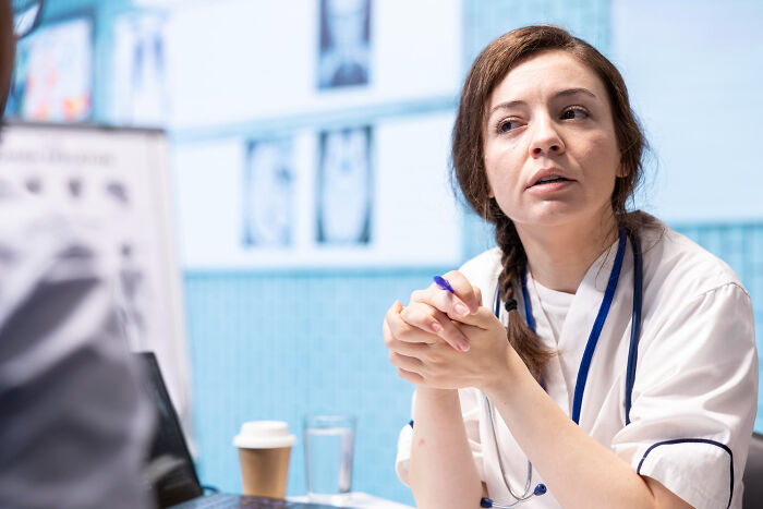 A thoughtful female doctor listening intently, representing interactions with patients.