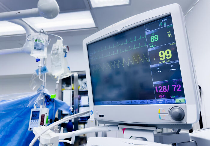 Medical monitor displaying patient vital signs and heart rate in a hospital or operating room.