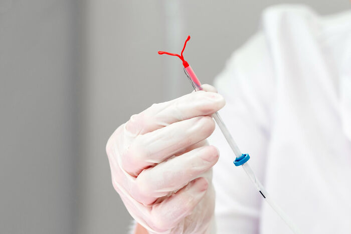 A healthcare professional wearing white gloves holds an IUD device, illustrating something patients have said to doctors.