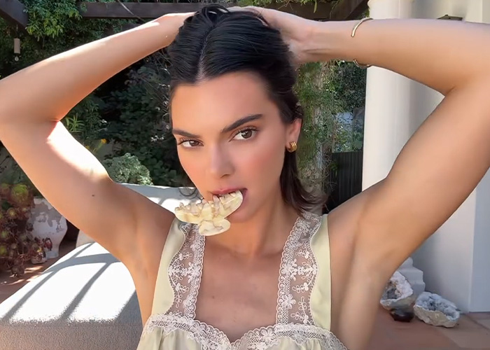 Kendall Jenner with a hair accessory, a claw clip, in her mouth, raising awareness about life threatening injuries from hair accessories.