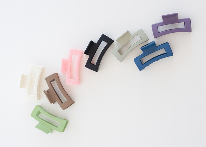 Colorful hair accessories, specifically hair claws, scattered on a white background, linked to life-threatening injuries.