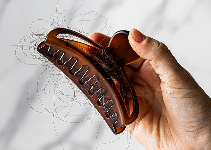 A hair accessory that can cause life-threatening injuries, held by a hand and filled with loose hair.