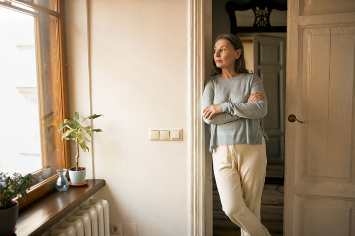 A controlling mom stands in a doorway, looking pensive, illustrating the struggle with her 22yo daughter. A controlling mom stands in a doorway, looking pensive, illustrating the struggle with her 22yo daughter.