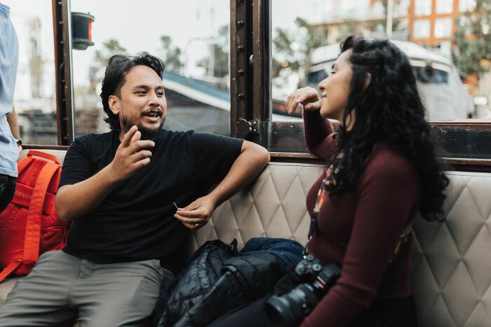 A conventionally attractive man and woman having a conversation on a boat.