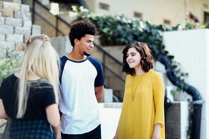 A group of friends laughing outdoors, sharing experiences about being conventionally attractive.