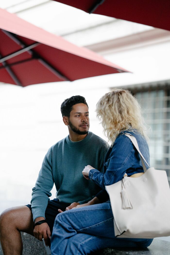 A conventionally attractive man and woman conversing outdoors. They appear to be on a date.