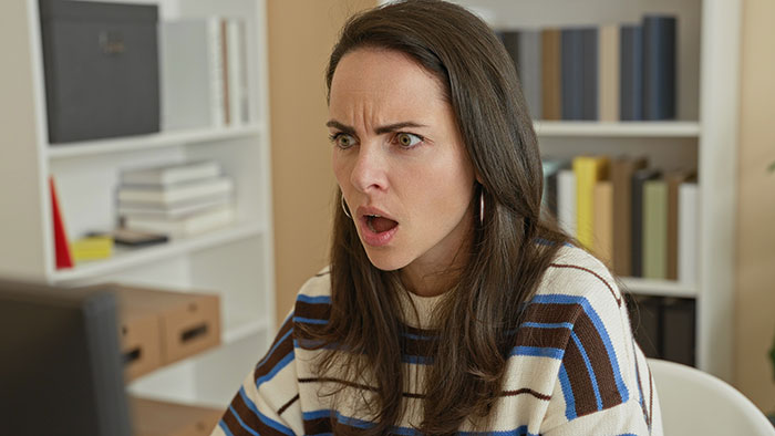 A babysitter looking shocked and confused at a computer, dealing with parents who gaslight her about a crying baby. A babysitter looking shocked and confused at a computer, dealing with parents who gaslight her about a crying baby.