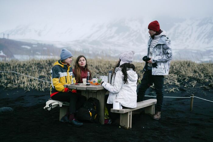 A group of Americans being respectful while visiting another country, enjoying a picnic in a snowy, mountainous landscape.