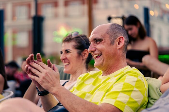 Happy tourists clapping at an outdoor event, remembering to be respectful when they visit other countries.