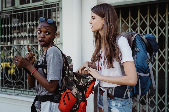 Two women with backpacks looking concerned, reminding Americans to be respectful when they visit other countries.