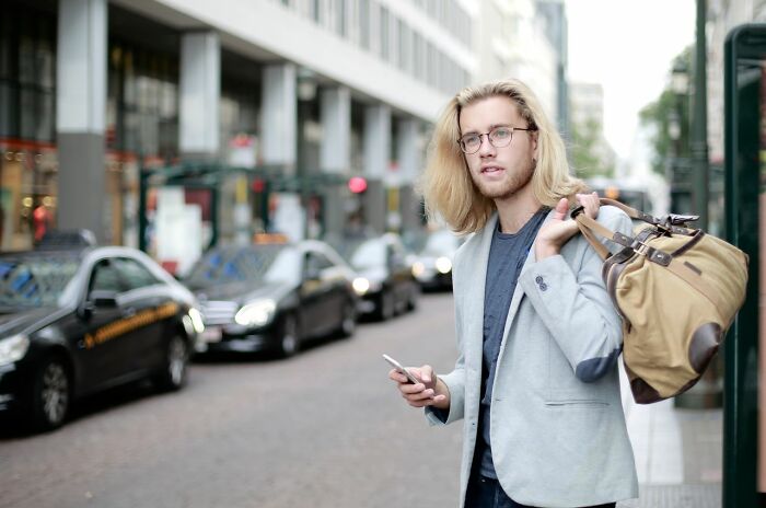 A man with a bag and phone on a city street, reminding Americans to be respectful when they visit other countries.