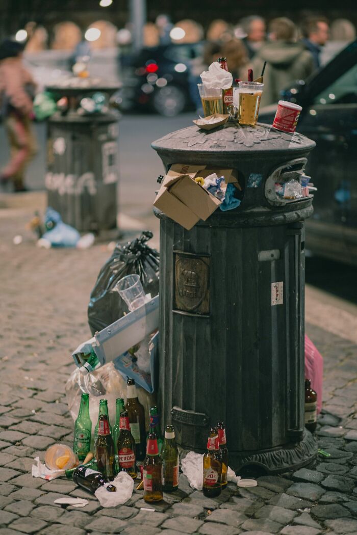 An overflowing trash can with litter on the street, illustrating awful stories that remind Americans to be respectful.