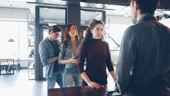 Tourists looking confused while talking to a hotel staff, highlighting the importance of being respectful when they visit other countries.