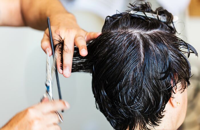 Hairdresser cutting a woman's hair, highlighting the pink taxes making being a woman more difficult.