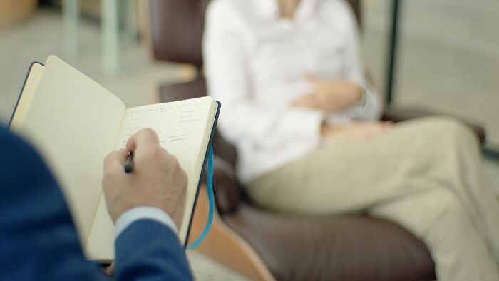 A person taking notes during a therapy session, highlighting challenges women face due to pink taxes.