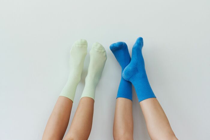 Two pairs of feet in different colored socks, showcasing how pink taxes make being a woman more difficult.