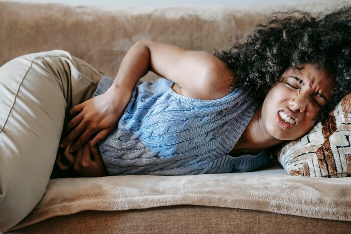 A woman suffering from period pain, representing the health-related costs and pink taxes for women.