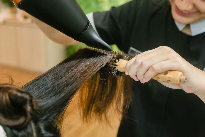 Pink taxes affecting women: A stylist blow-drying a woman's hair, showing the cost of beauty services for women.