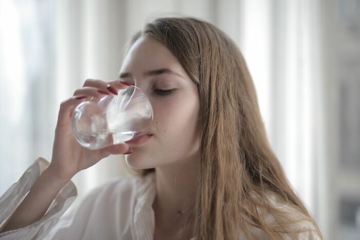 A young woman drinking water, illustrating the impact of pink taxes on women's everyday lives.