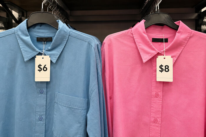 Two shirts with price tags, a blue shirt costing $6 and a pink shirt costing $8, symbolizing pink taxes.