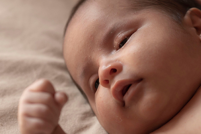 Close-up of a newborn baby's face, illustrating the early impact of pink taxes on being a woman.