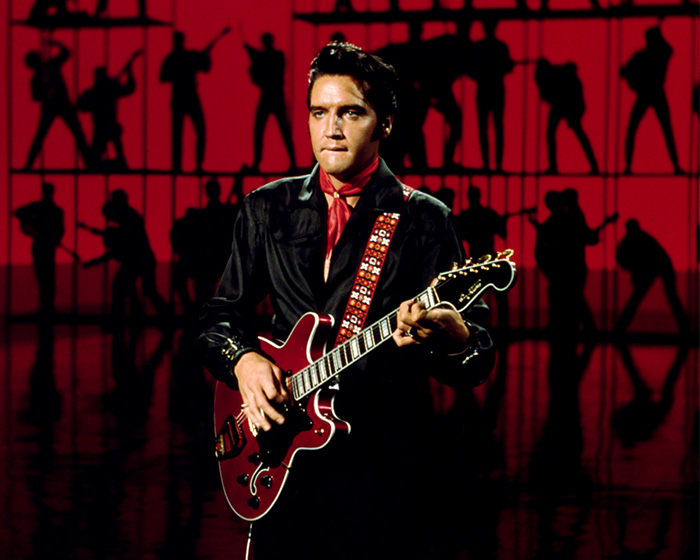 Elvis Presley on stage with his guitar, representing a feuds and controversies Dolly Parton story.