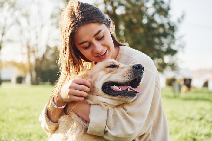 A woman happily embracing her golden retriever, experiencing a sign from the universe with her beloved pet.