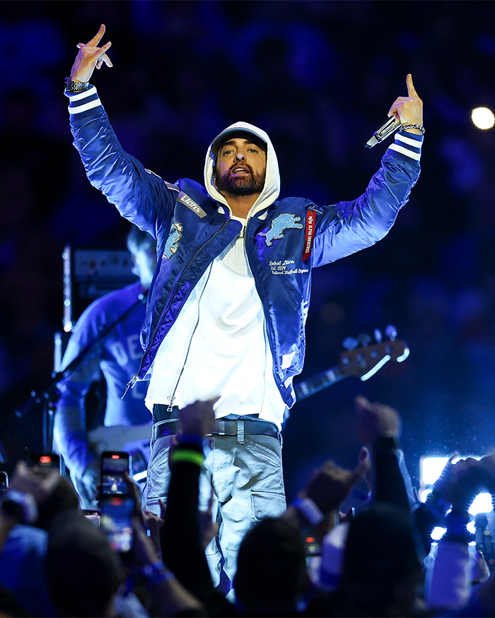 Eminem performing on stage, arms raised, facing backlash after sharing Dolly Parton letter.