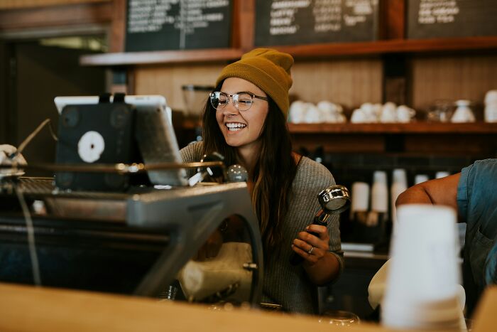 A smiling retail worker behind a counter, embodying positive customer interactions.