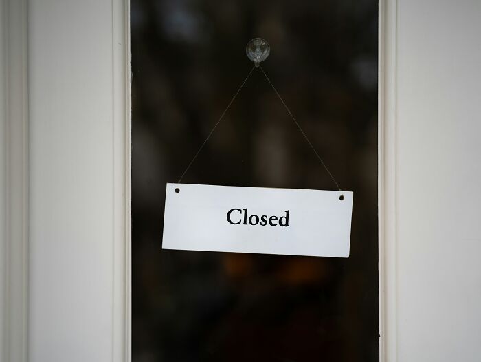 Closed sign on a glass door, representing a pause in retail customer interactions.