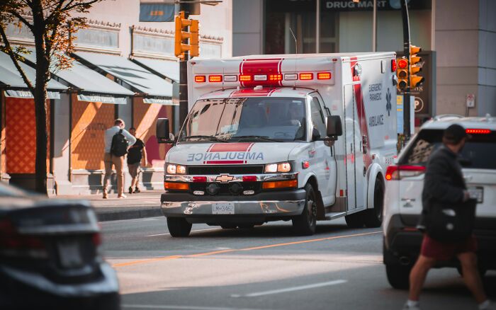 An ambulance with its lights on driving on a city street, reflecting urgent customer interactions.