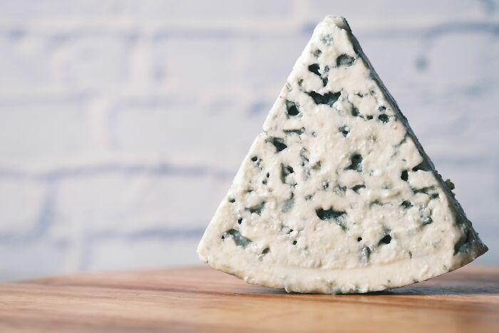 A slice of blue cheese on a wooden board, representing customer interactions in retail.