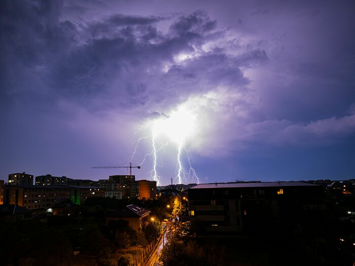 Lightning striking over a city skyline at night, symbolizing challenging customer interactions for retail workers.