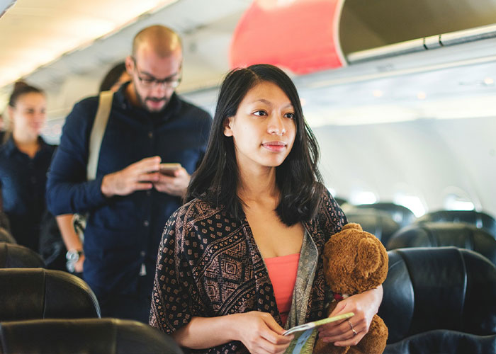 A woman on a plane is looking confused after finding her mom sitting in her plane seat. A woman on a plane is looking confused after finding her mom sitting in her plane seat.