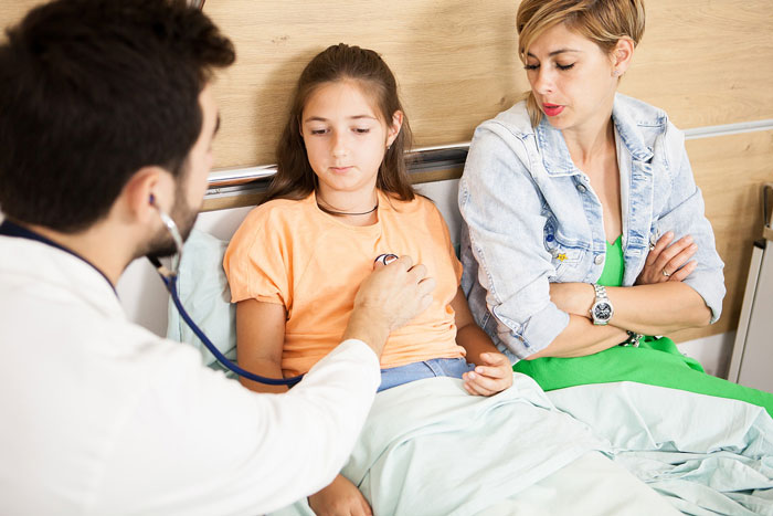A medical worker examines a child while a mom watches, unaware of the medical worker's prosthetic ear, mistakenly thinking it's a Halloween costume. A medical worker examines a child while a mom watches, unaware of the medical worker's prosthetic ear, mistakenly thinking it's a Halloween costume.