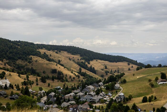 Europe suffers brutal drought: a general view of a European valley with green hills and a small village under a cloudy sky.